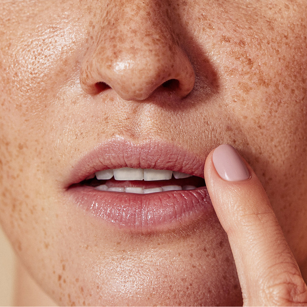 close up of finger touching side of lips